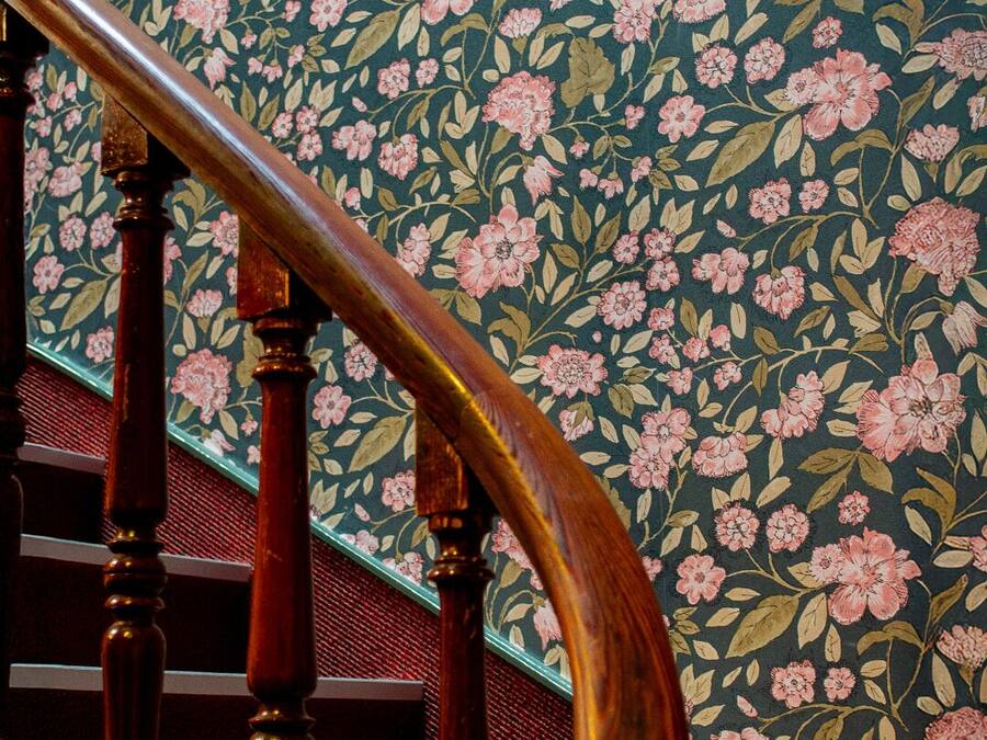 Una escalera de madera con un fondo de papel tapiz floral.