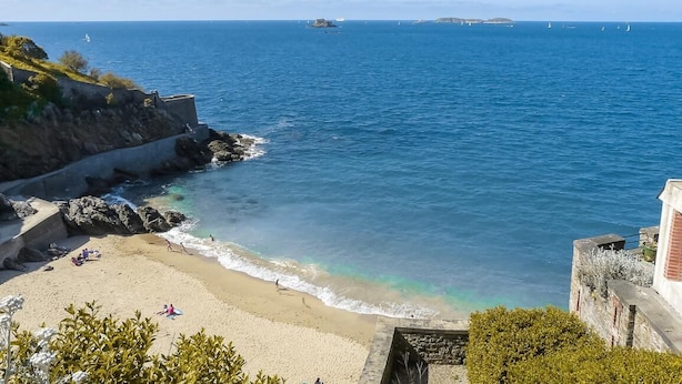 Vista costera con una playa arenosa, acantilados rocosos y el mar.