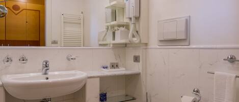 A bathroom with a sink, toilet, bidet, and a mirror.