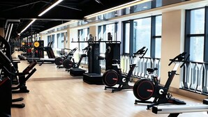 Une salle de sport équipée de machines de cardio, de matériel de musculation et dotée de grandes fenêtres.