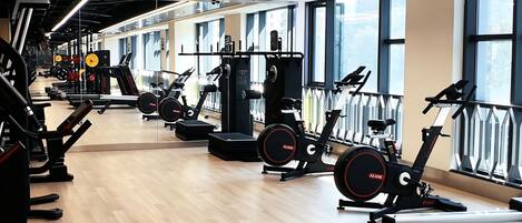 A gym with cardio machines, weightlifting equipment, and large windows.