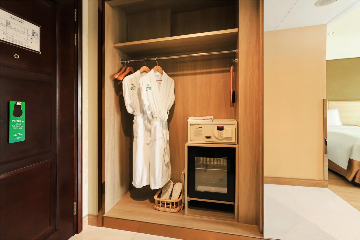 A wooden wardrobe with hanging robes, a microwave, and a shoe rack.
