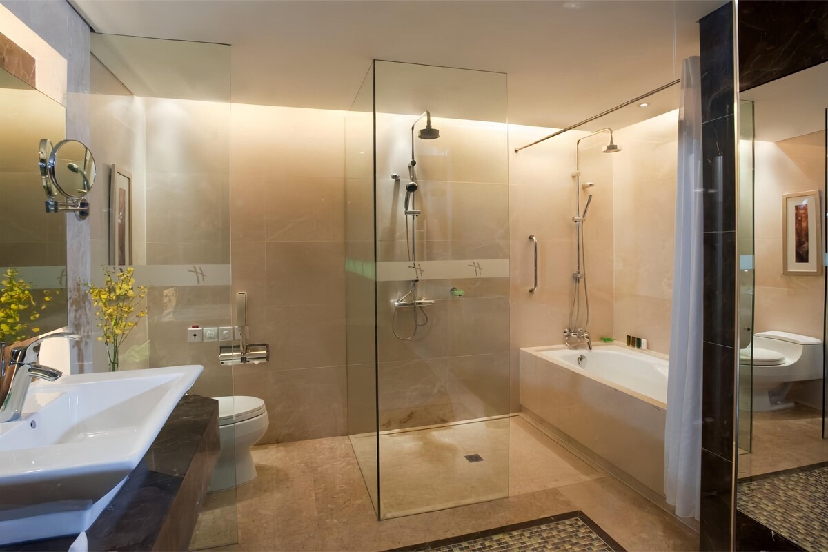 A modern bathroom with a glass-enclosed shower, a separate bathtub, and a large vanity with a sink.