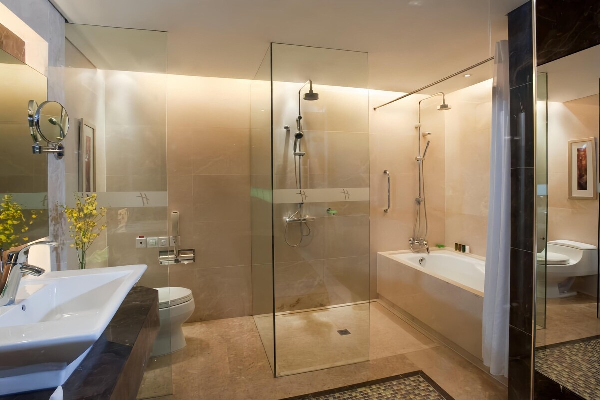 Un baño moderno con ducha de vidrio, bañera separada y un mueble de tocador grande con lavabo.