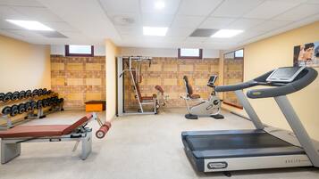Un gimnasio con cinta de correr, mancuernas y máquinas de pesas.