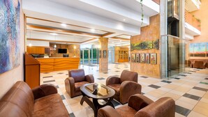 A lobby with a checkered floor, leather seating, a reception desk, and artwork on the walls. - Hotel Aquarell (Cegled)