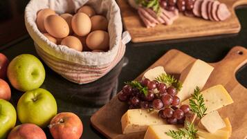 Diversos alimentos, como huevos, queso, uvas y manzanas, sobre una tabla de madera.