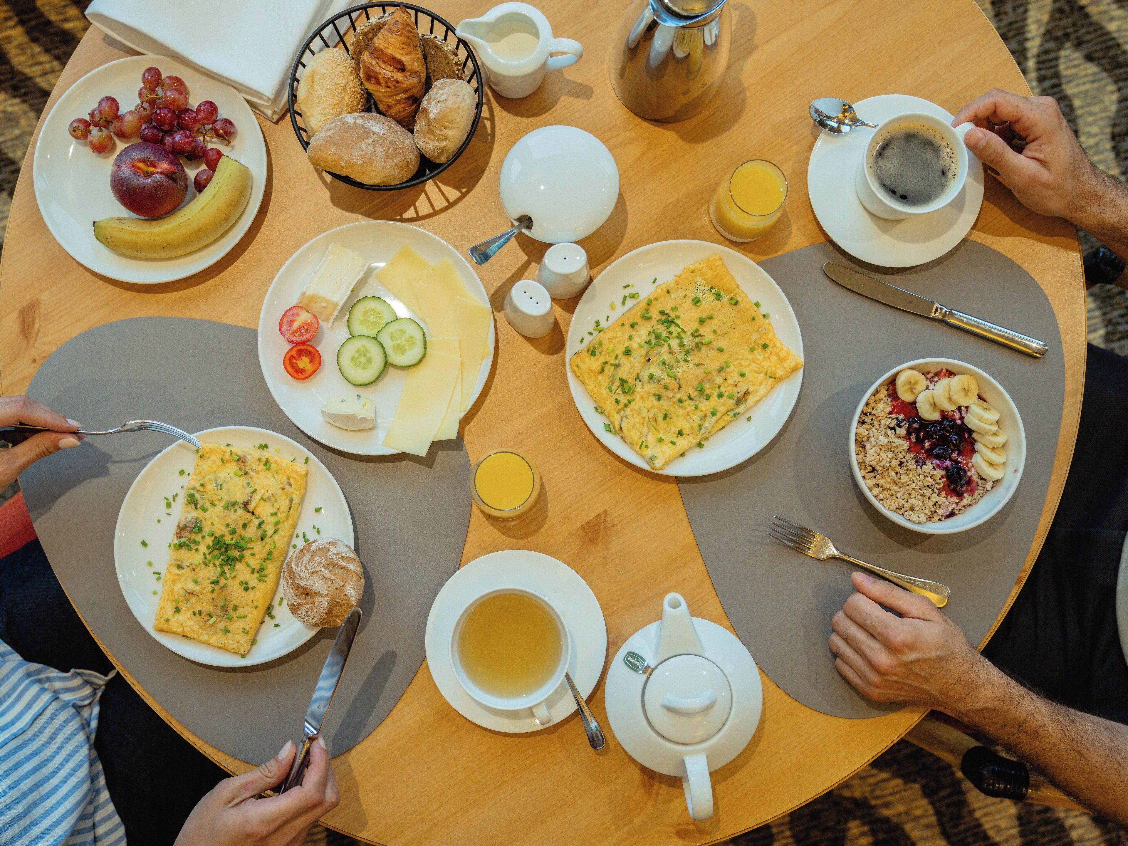 Una mesa redonda con alimentos para el desayuno, como huevos, tostadas, fruta y bebidas.