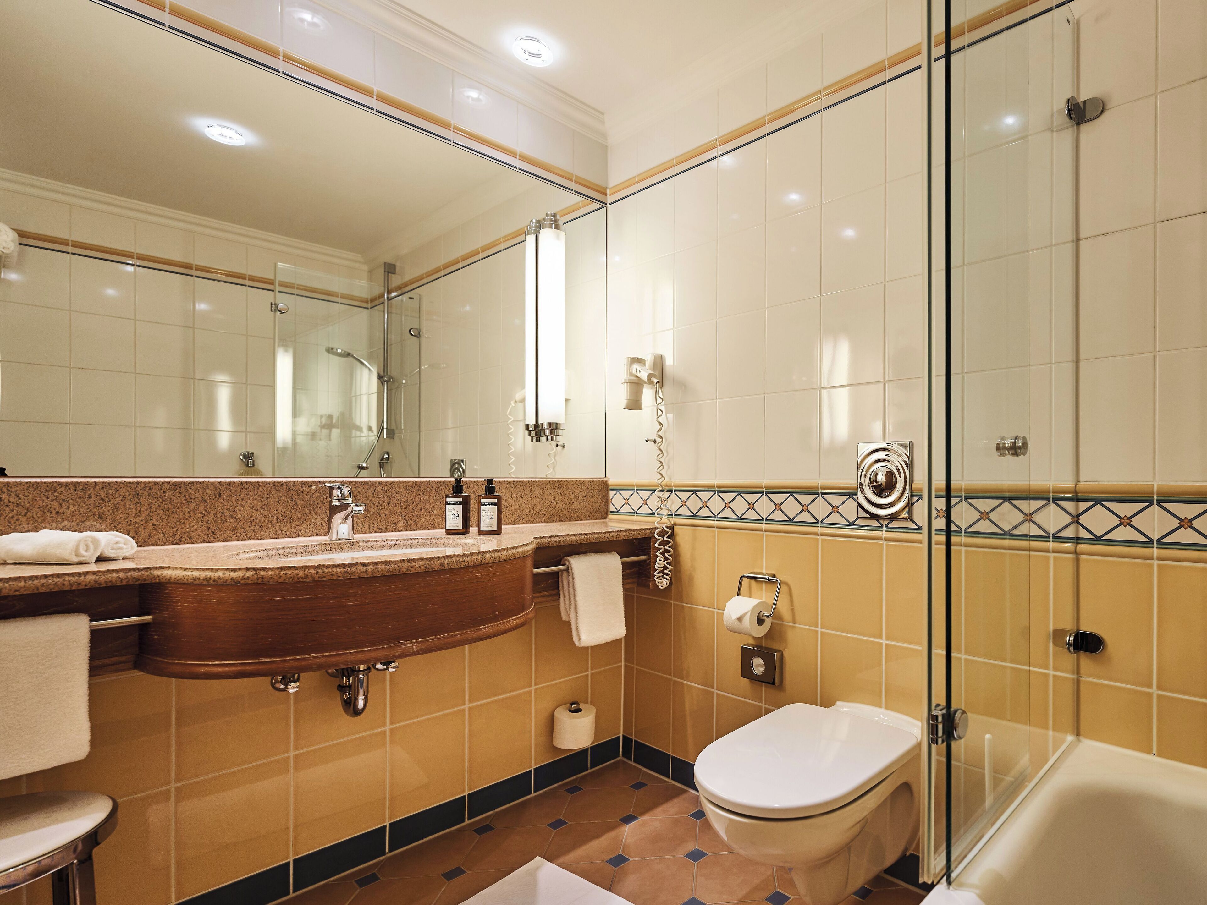Ein Badezimmer mit Waschbecken, Spiegel, Toilette und Dusche.
