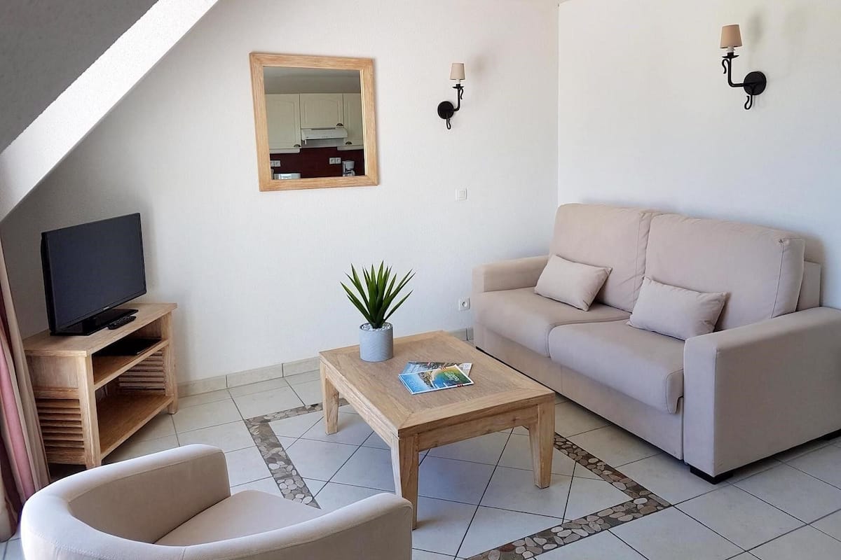 A modern living room with a sofa, a coffee table, a TV, and a plant.