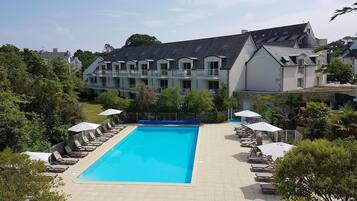 En sÀsongsöppen utomhuspool, parasoller och solstolar