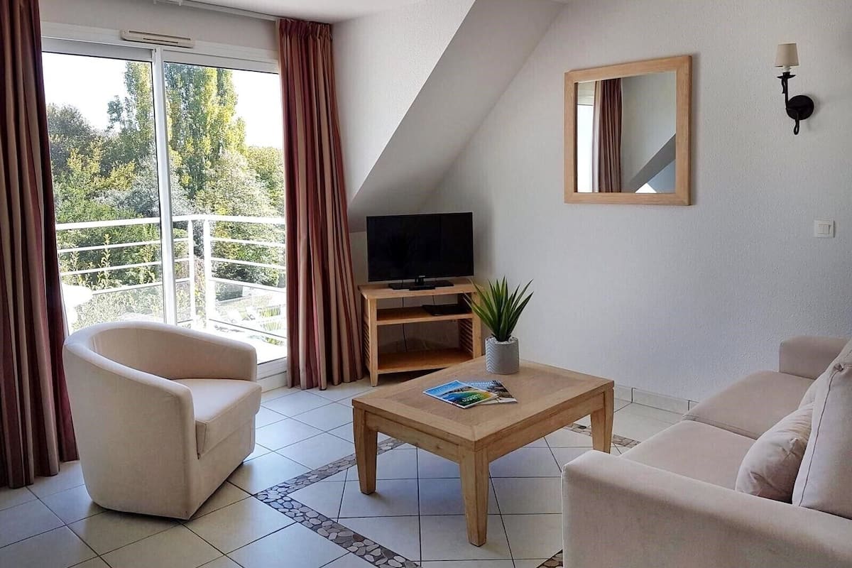 A modern living room with a sofa, a coffee table, a TV on a wooden stand, and a potted plant.