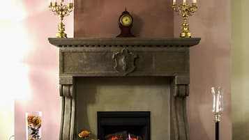 A fireplace with a clock above it, surrounded by decorative items and a patterned rug.