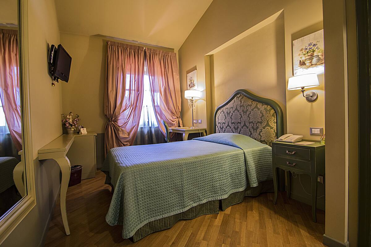 A hotel room with two beds, a desk, a chair, a lamp, and a telephone.