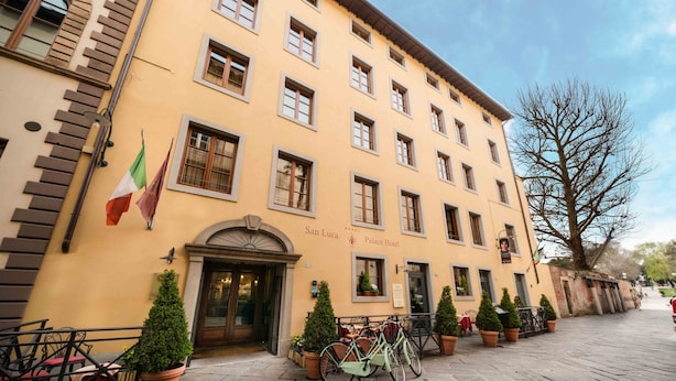 Hotelli, jonka julkisivu on keltainen, siinä on useita ikkunoita ja kyltti, jossa lukee: ”San Luca Palace Hotel”.