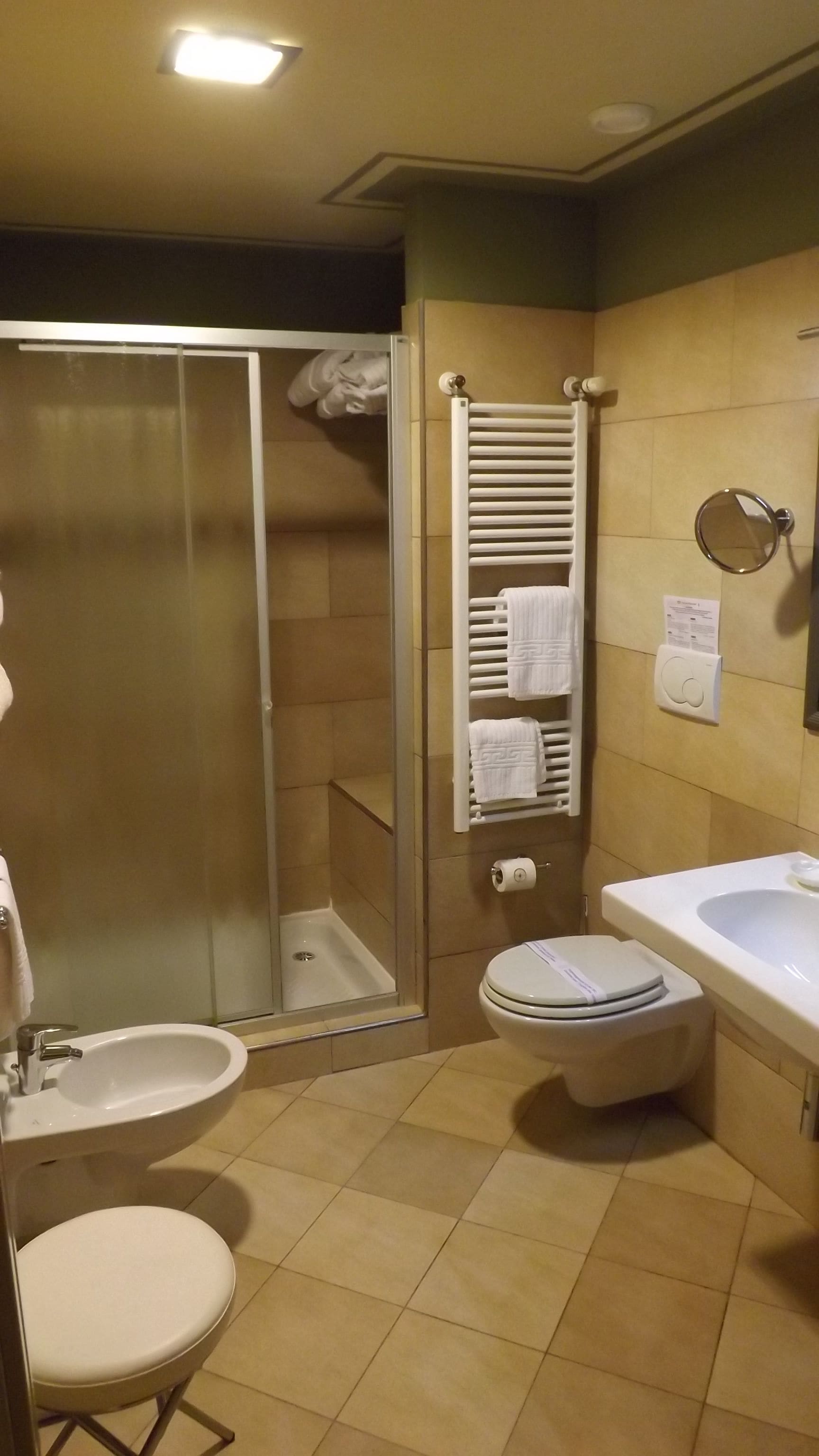 Baño con ducha, inodoro, lavamanos y toallero.