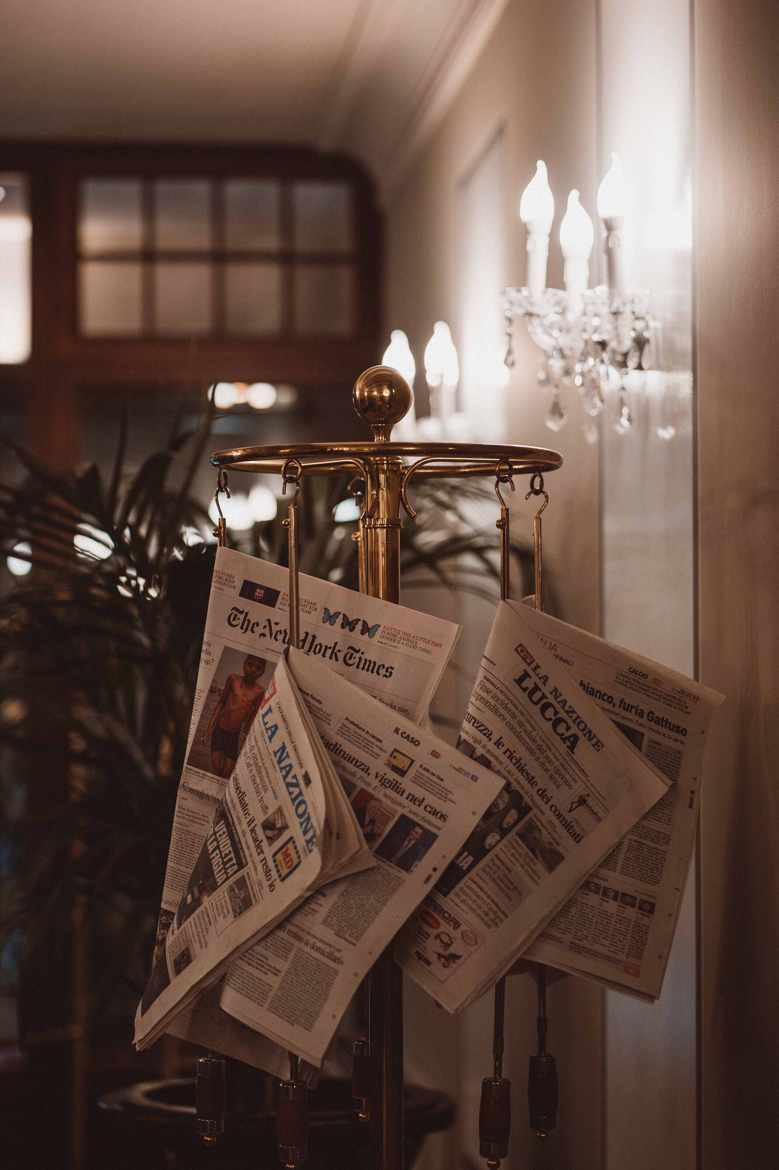 Un candelabro con numerosas velas, rodeado de periódicos en varios idiomas.