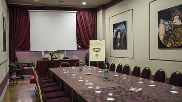 Una sala de conferencias con una larga mesa, sillas, una pantalla de proyector y obras de arte en las paredes.