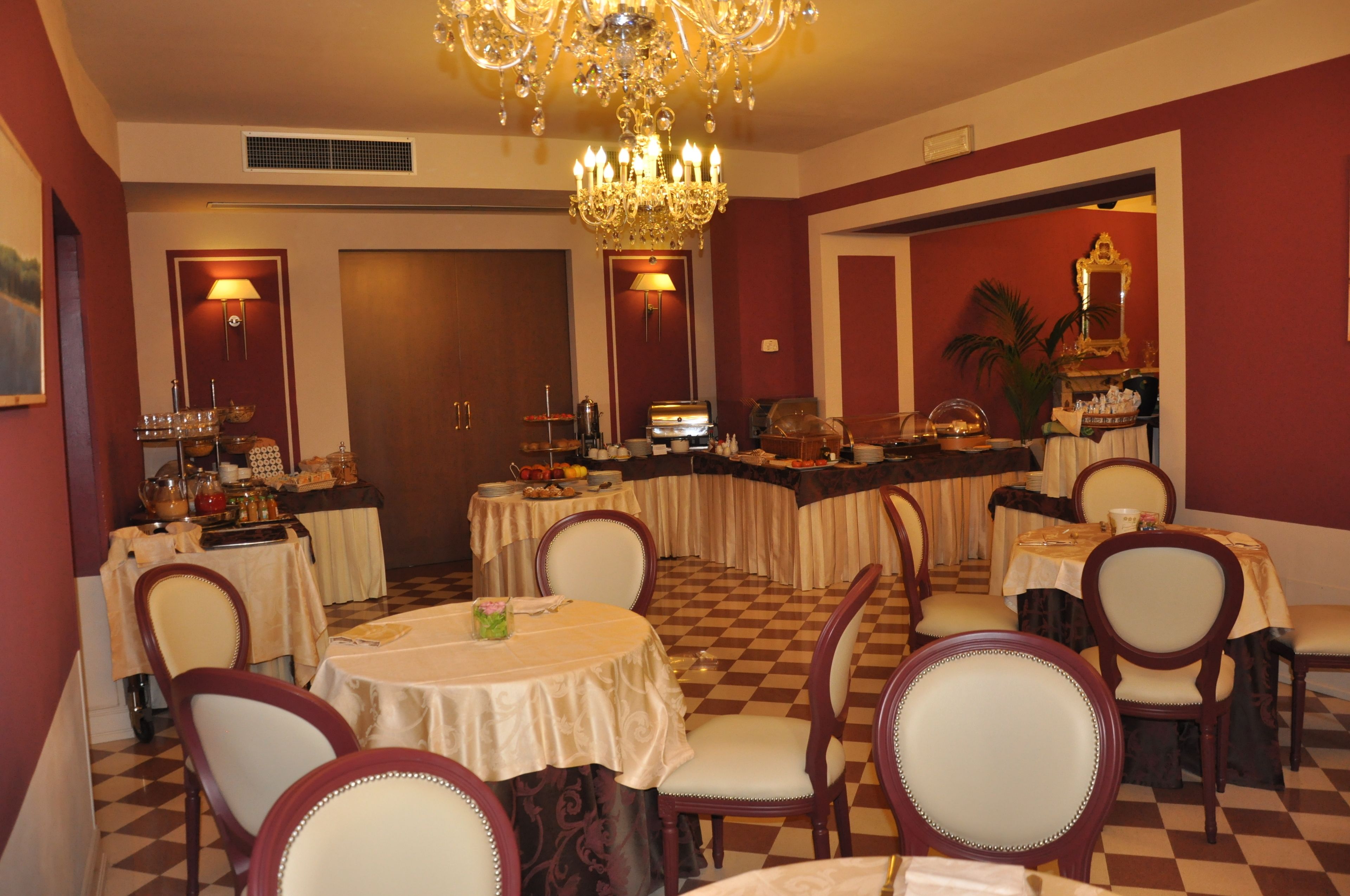 A dining area with round tables and chairs, a chandelier, and a checkered floor.