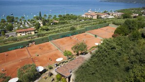 A tennis court with a view of the sea and mountains in the background.