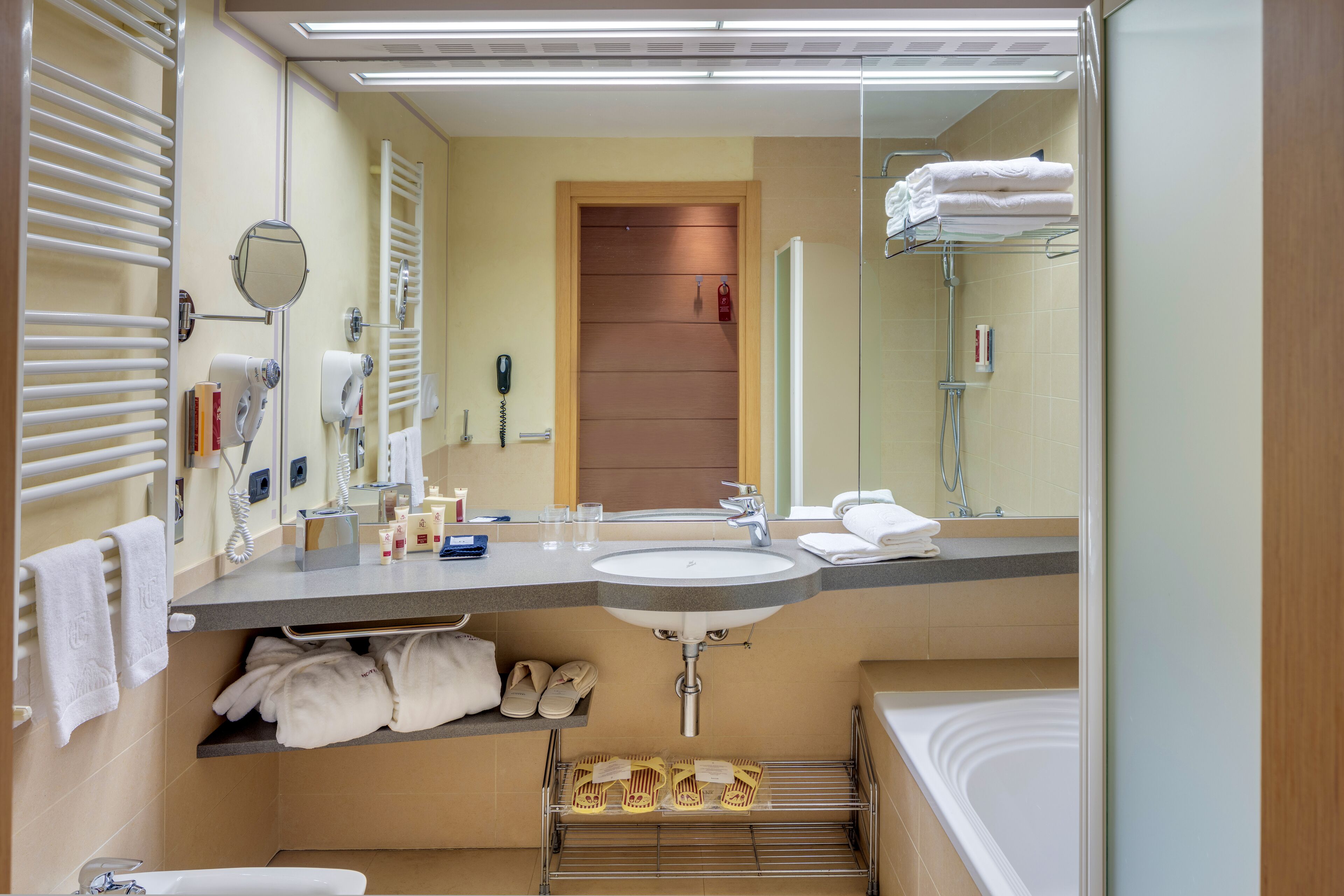 A modern bathroom with a sink, mirror, towel rack, and a shower area.