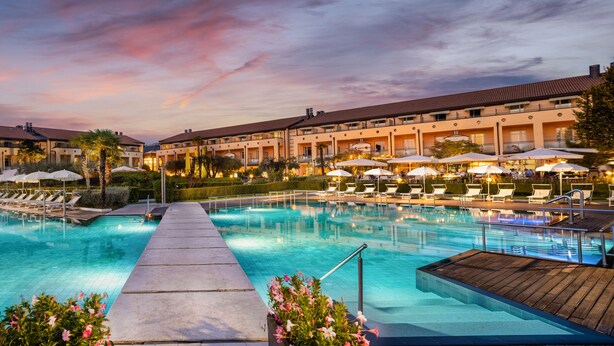 A hotel pool area with a clear walkway, lounge chairs, and umbrellas.