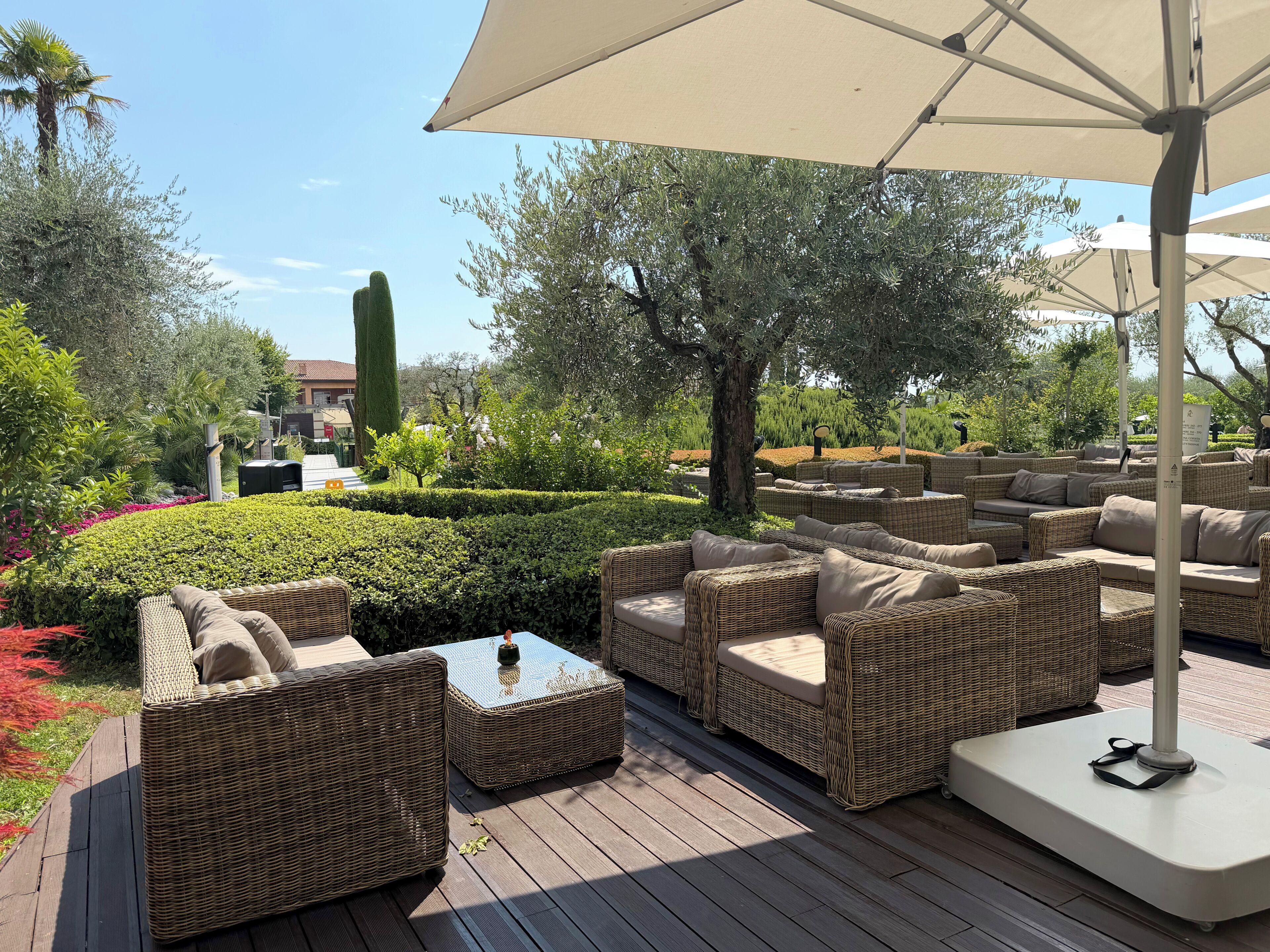 Un área de estar al aire libre con muebles de mimbre y un paraguas grande.