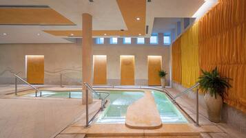 A pool area with two pools, a staircase, and a large potted plant.