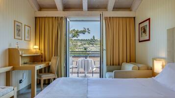 A hotel room with a bed, desk, chair, and a balcony with a table and chairs.