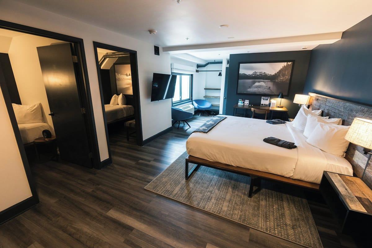 Ein modernes Hotelzimmer mit einem großen Bett, einem Schreibtisch, einem Stuhl, einem Fernseher und Blick auf ein Gewässer.