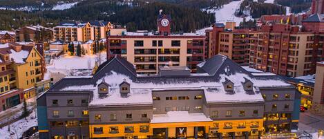A hotel with multiple floors, a prominent clock tower, and a snowy mountain backdrop.