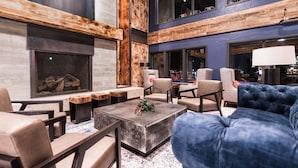 A modern lounge area with a fireplace, seating, and a large window. - Gravity Haus Breckenridge (Breckenridge)