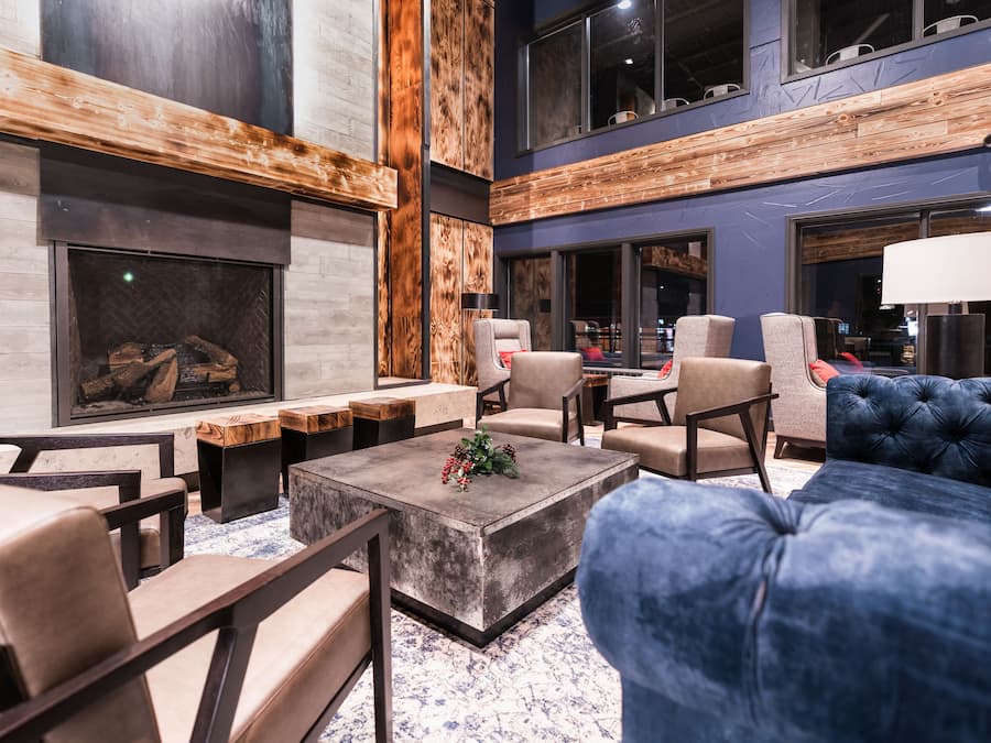 Un área de estar moderna con chimenea, asientos y un ventanal grande.