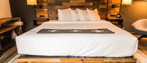 A neatly made bed with a wooden headboard, two bedside lamps, and a wall-mounted clock.