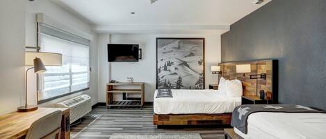 Een hotelkamer met een bed, bureau, stoel en een groot schilderij aan de muur.