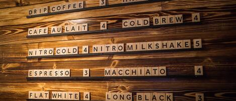 Pared de madera con baldosas que forman palabras y números relacionados con el café.