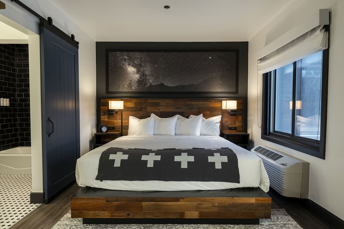 Ein Schlafzimmer mit Bett, Wandgemälde mit Sternenhimmel, Fenster und Holz-Kopfteil.