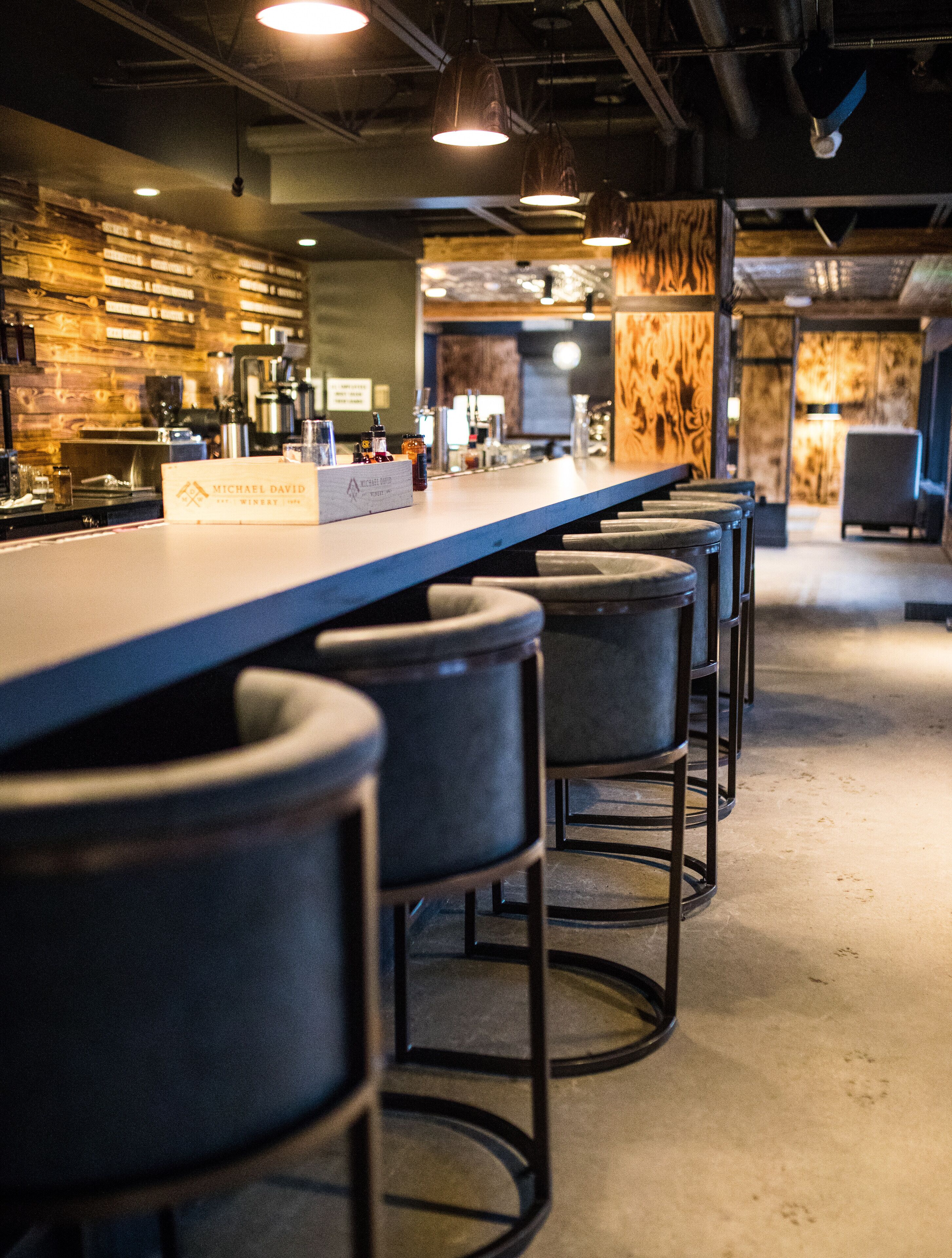 A bar area with a long counter and multiple stools.