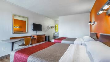 Camera d'albergo con due letti, una scrivania con sedia, televisione e uno specchio.