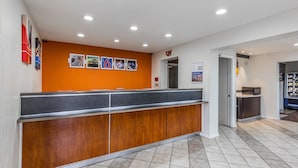 A reception area with a wooden counter, a tiled floor, and a wall with framed pictures. - Motel 6 Mount Vernon, IL (Mount Vernon)