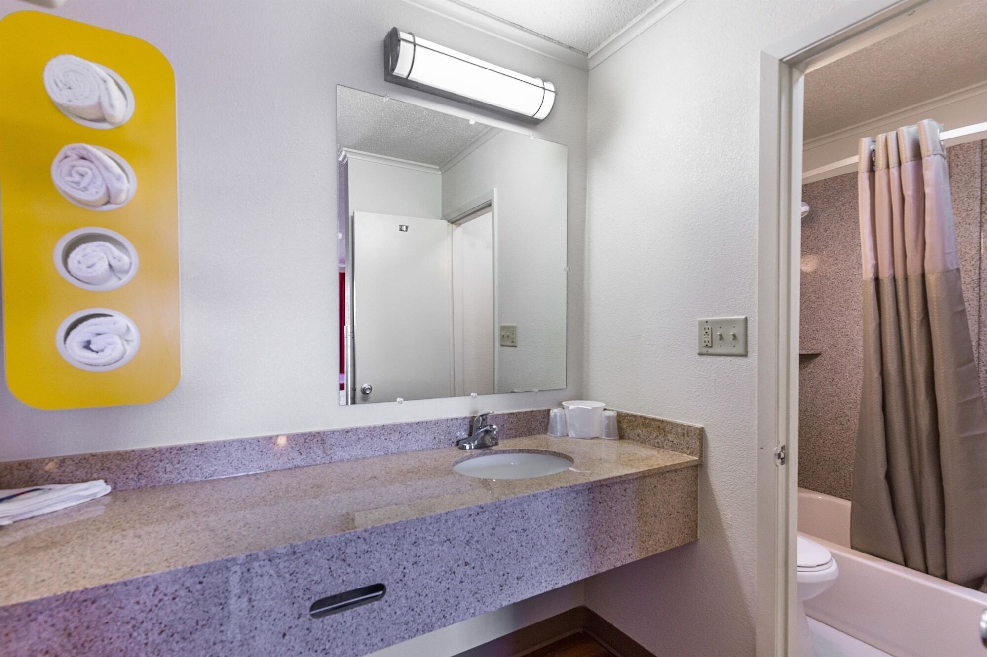 A bathroom with a granite countertop, a sink, a mirror, and a shower curtain.