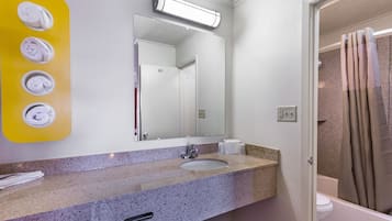 A bathroom with a granite countertop, a sink, a mirror, and a shower curtain.