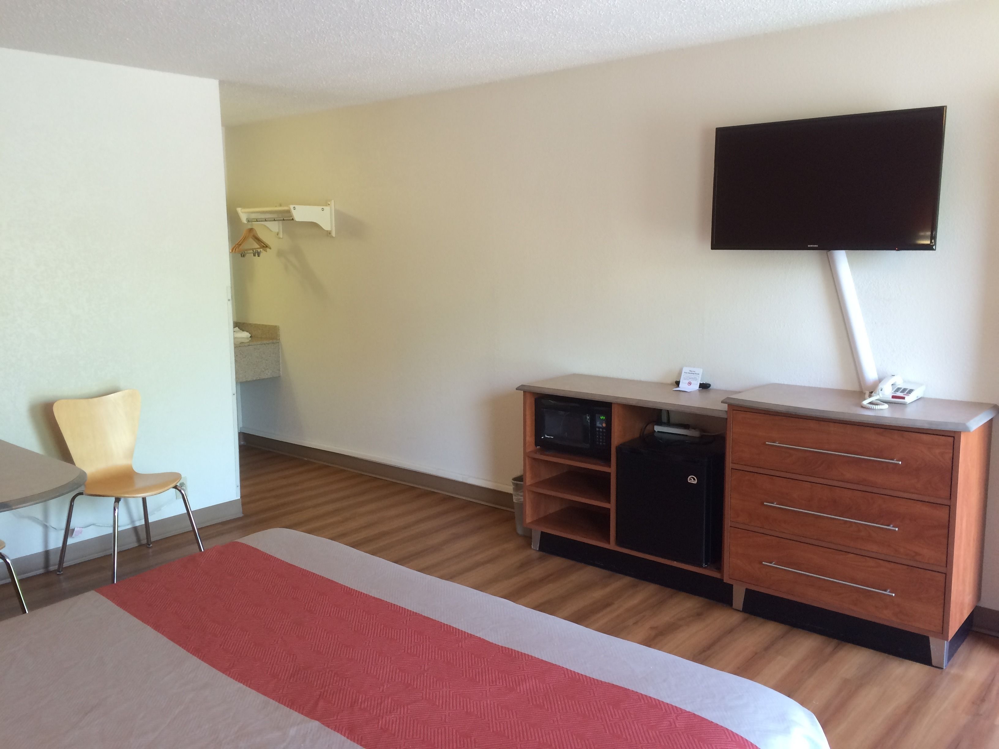 Camera d'albergo con un letto, una scrivania, una sedia, una TV, un forno a microonde e un minibar.