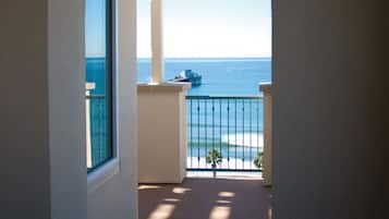 A corridor leading to a balcony with a view of the ocean.