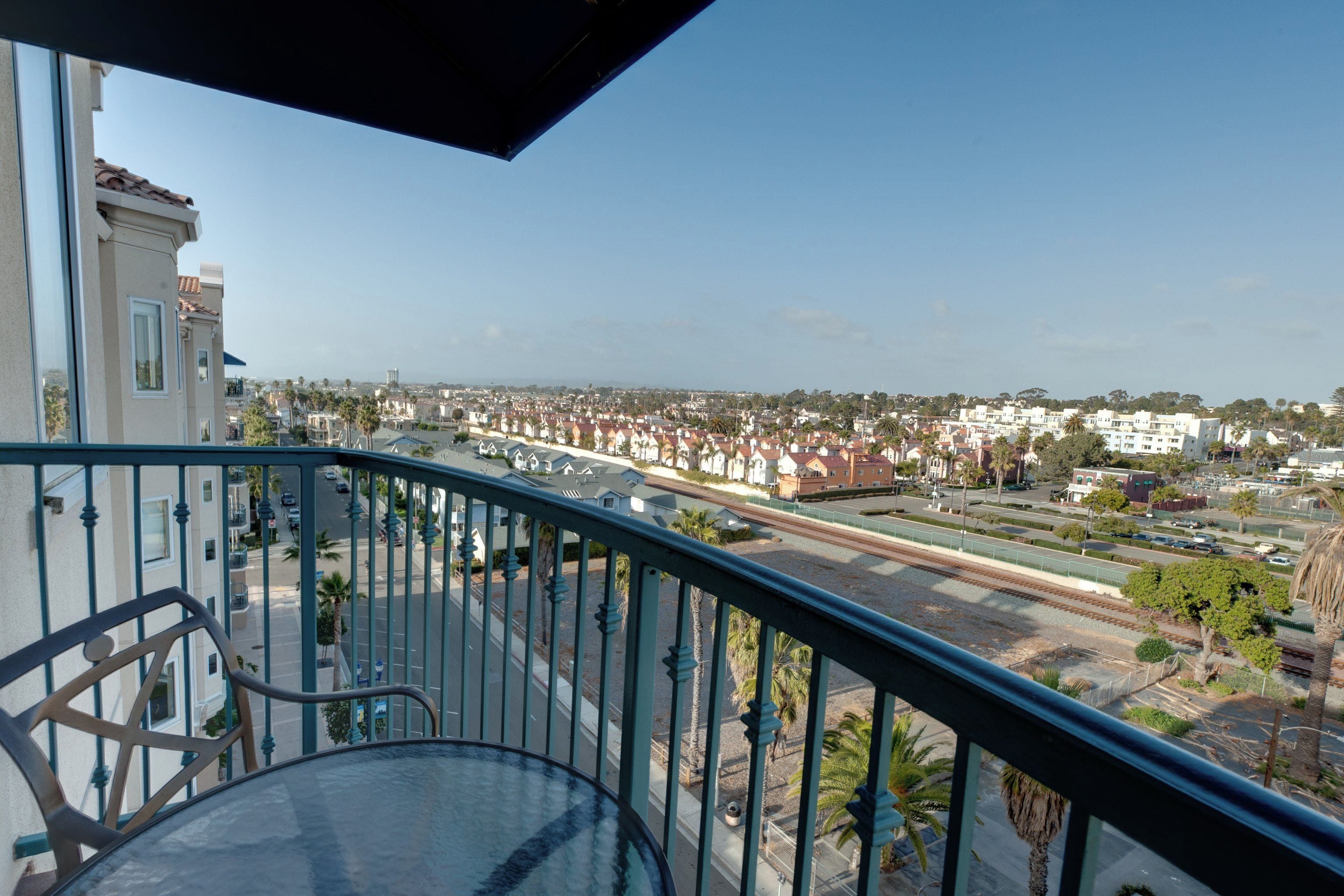 Un balcon donnant sur un quartier résidentiel, avec vue sur des maisons et une route.