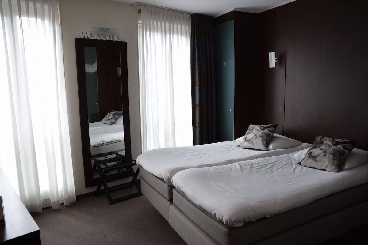 Ein Hotelzimmer mit zwei Betten, einem Schreibtisch und einem Spiegel.