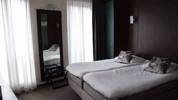 A hotel room with two beds, a desk, and a mirror.