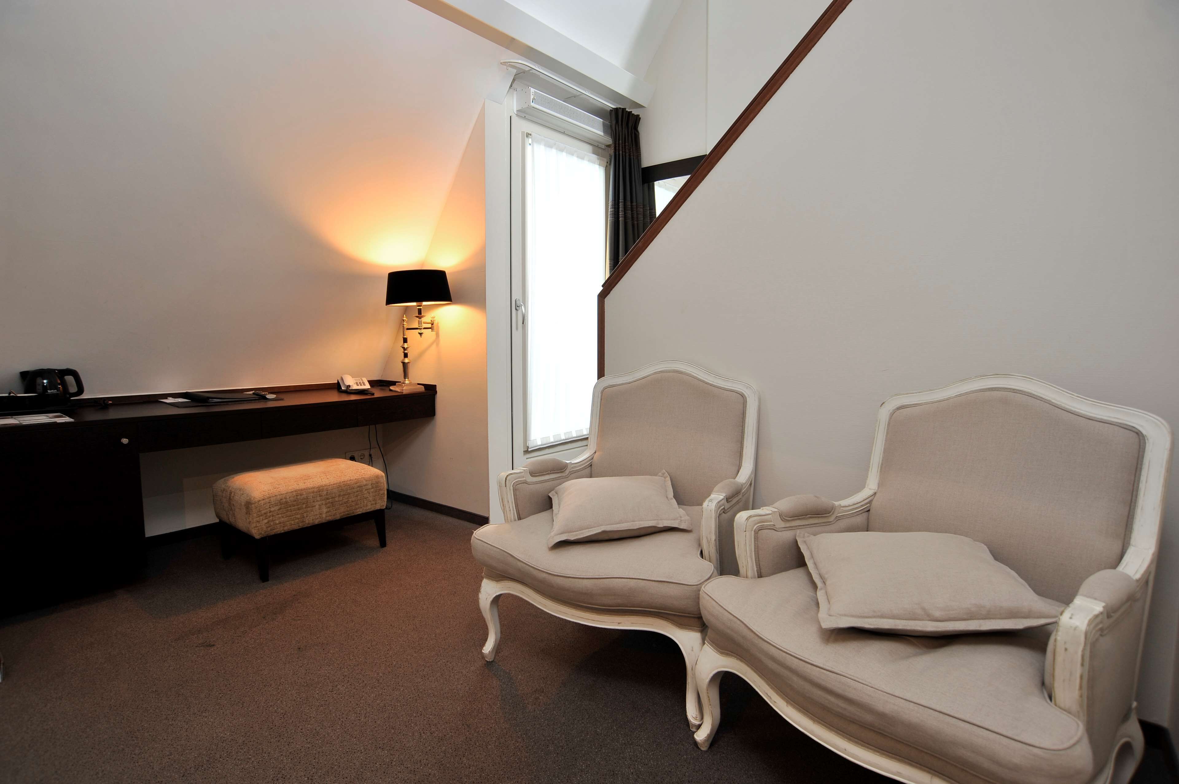 A bedroom with a bed, a desk, a chair, and a window.