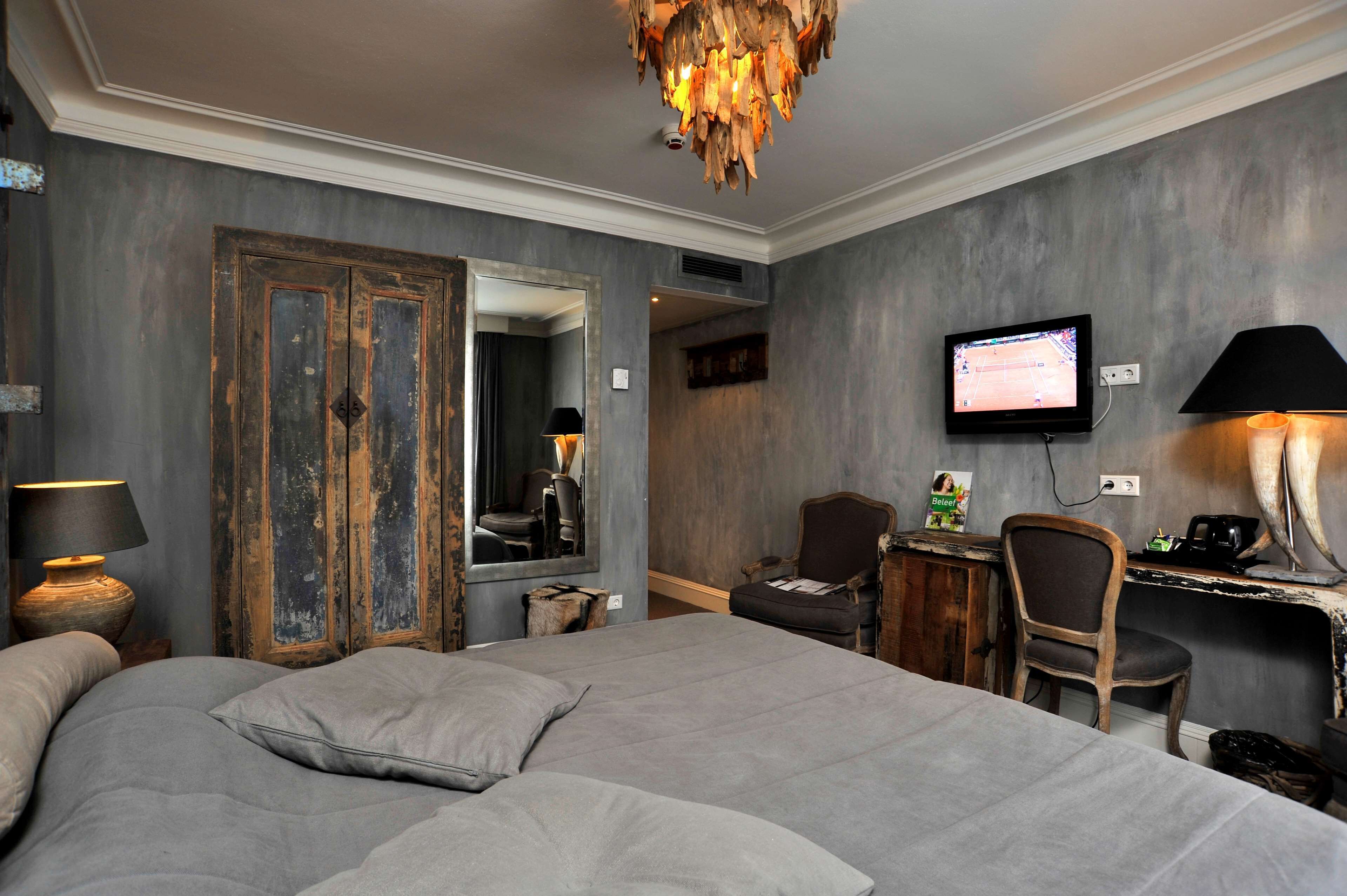 Un dormitorio con una cama grande, un escritorio con silla, un televisor y un espejo.