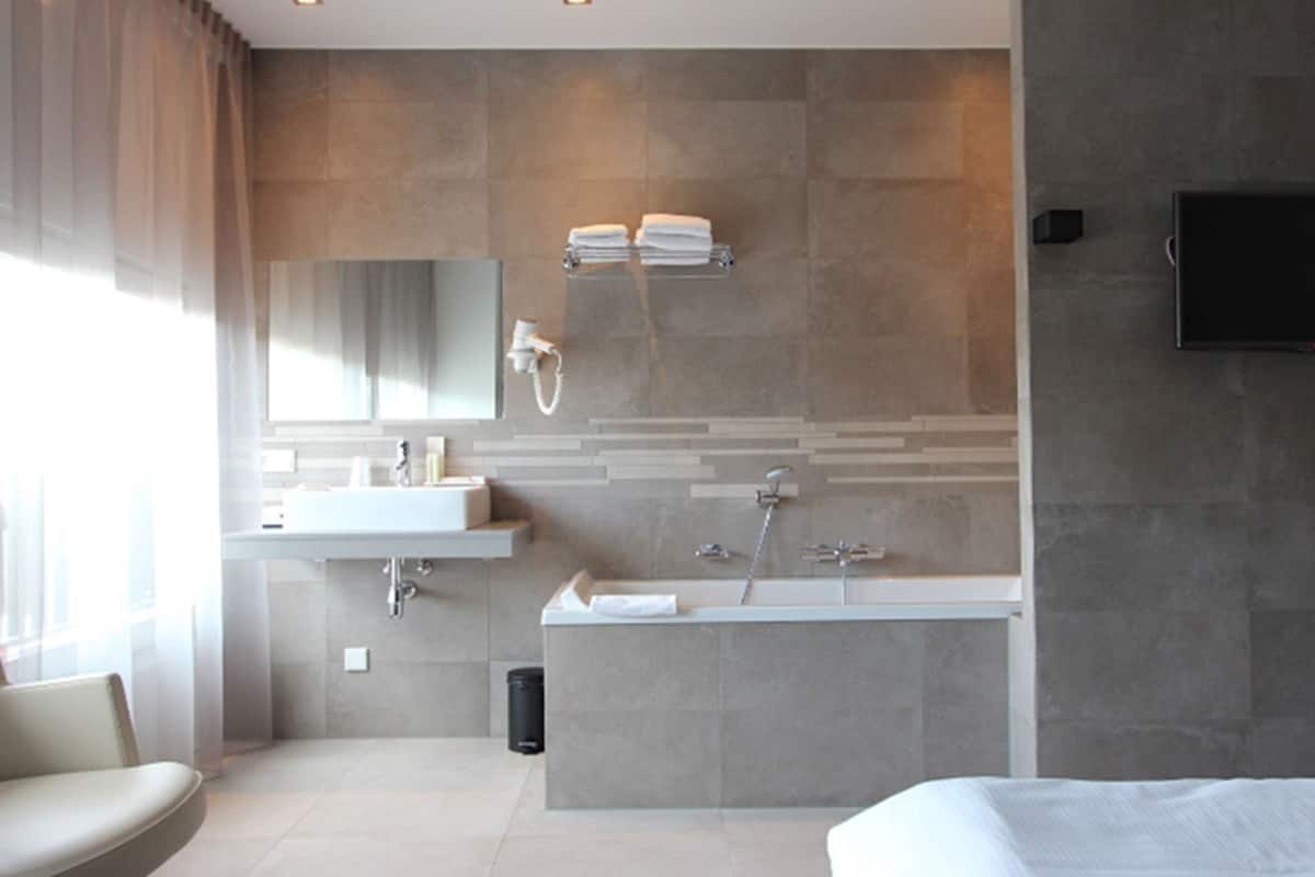 Ein modernes Badezimmer mit einer großen Badewanne, einem Waschbecken mit Spiegel und einem Handtuchhalter.